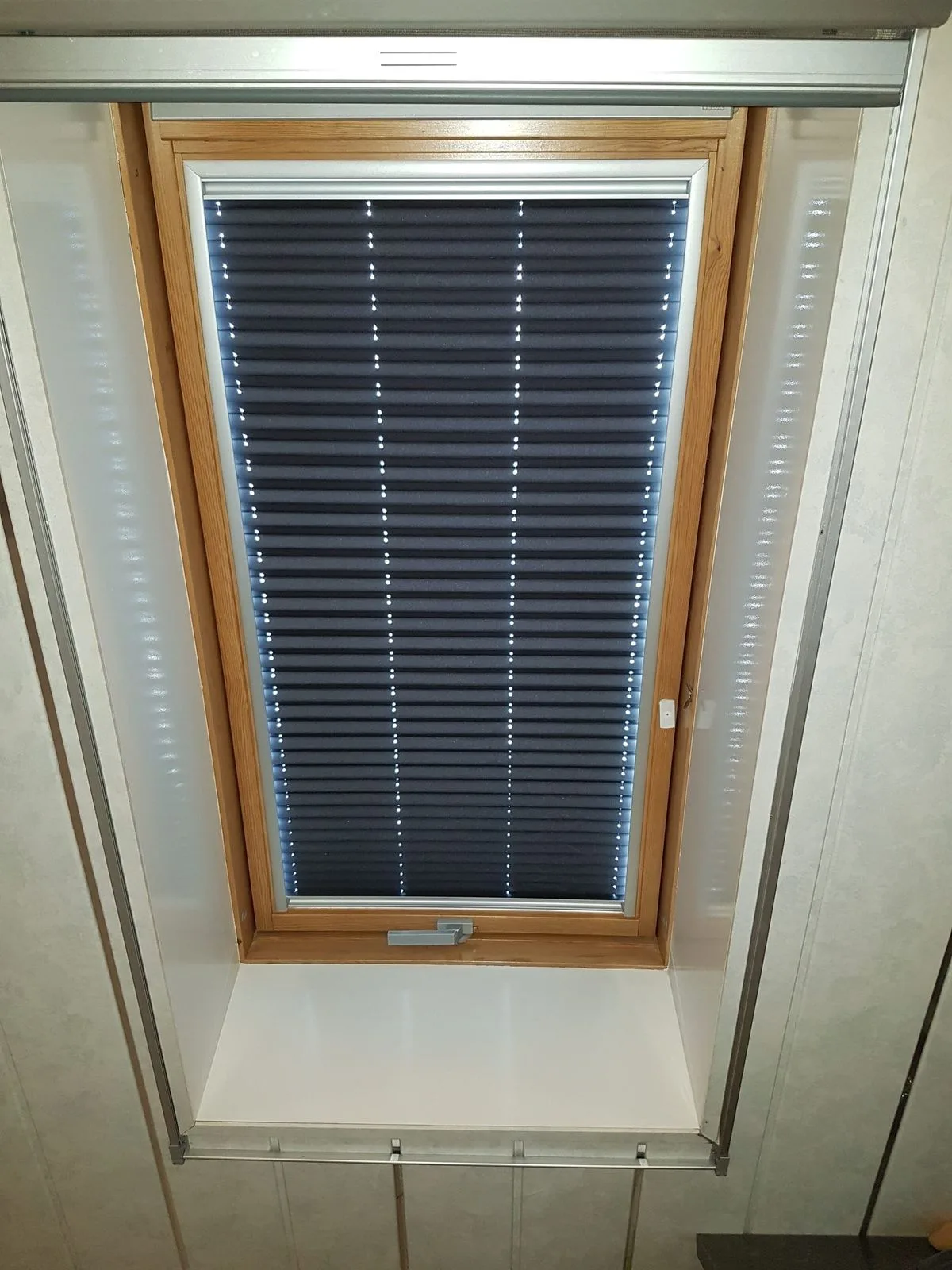 Donkerblauw plissé in een houten Velux-dakraam