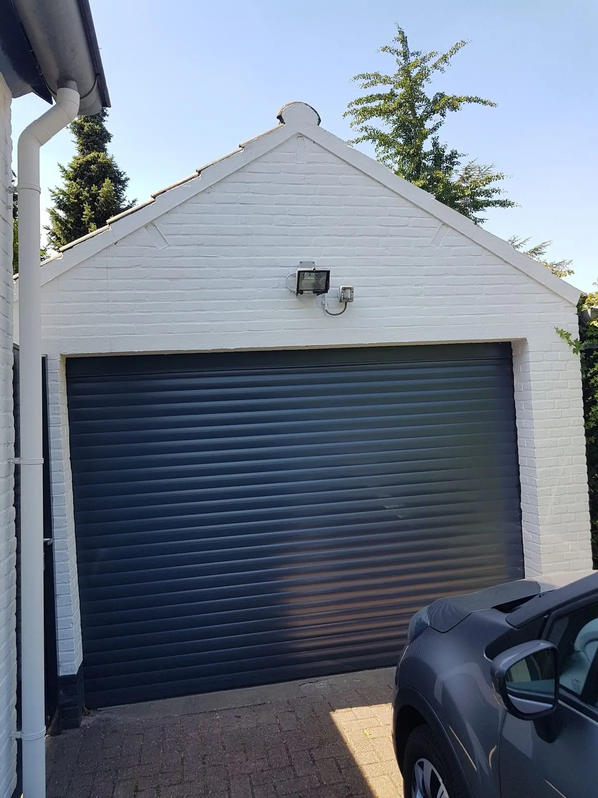 Antracietgrijze rolpoort in een witte garage met puntdak