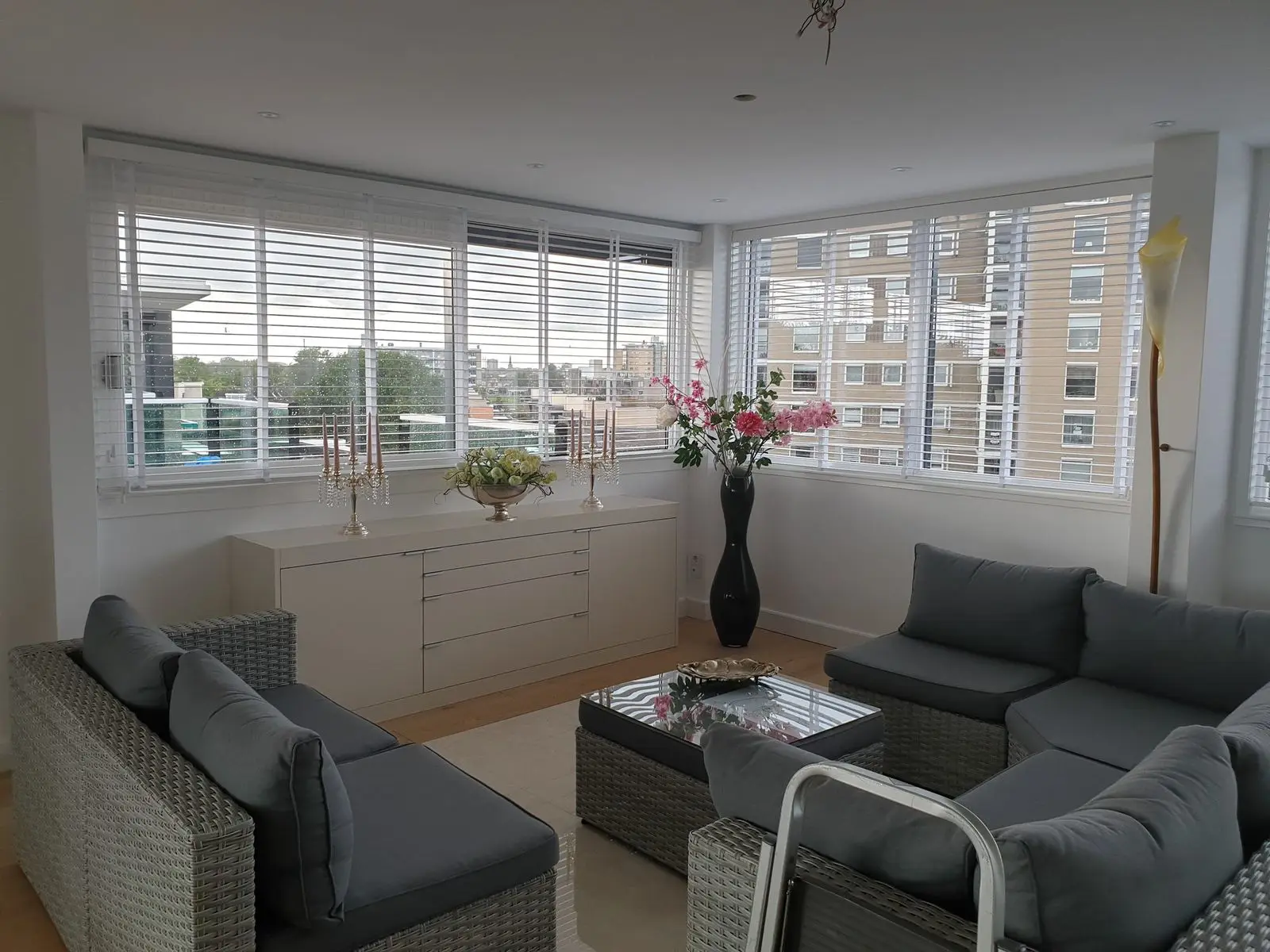 Witte jaloezieën voor een hoekraam in een woonkamer met loungebank