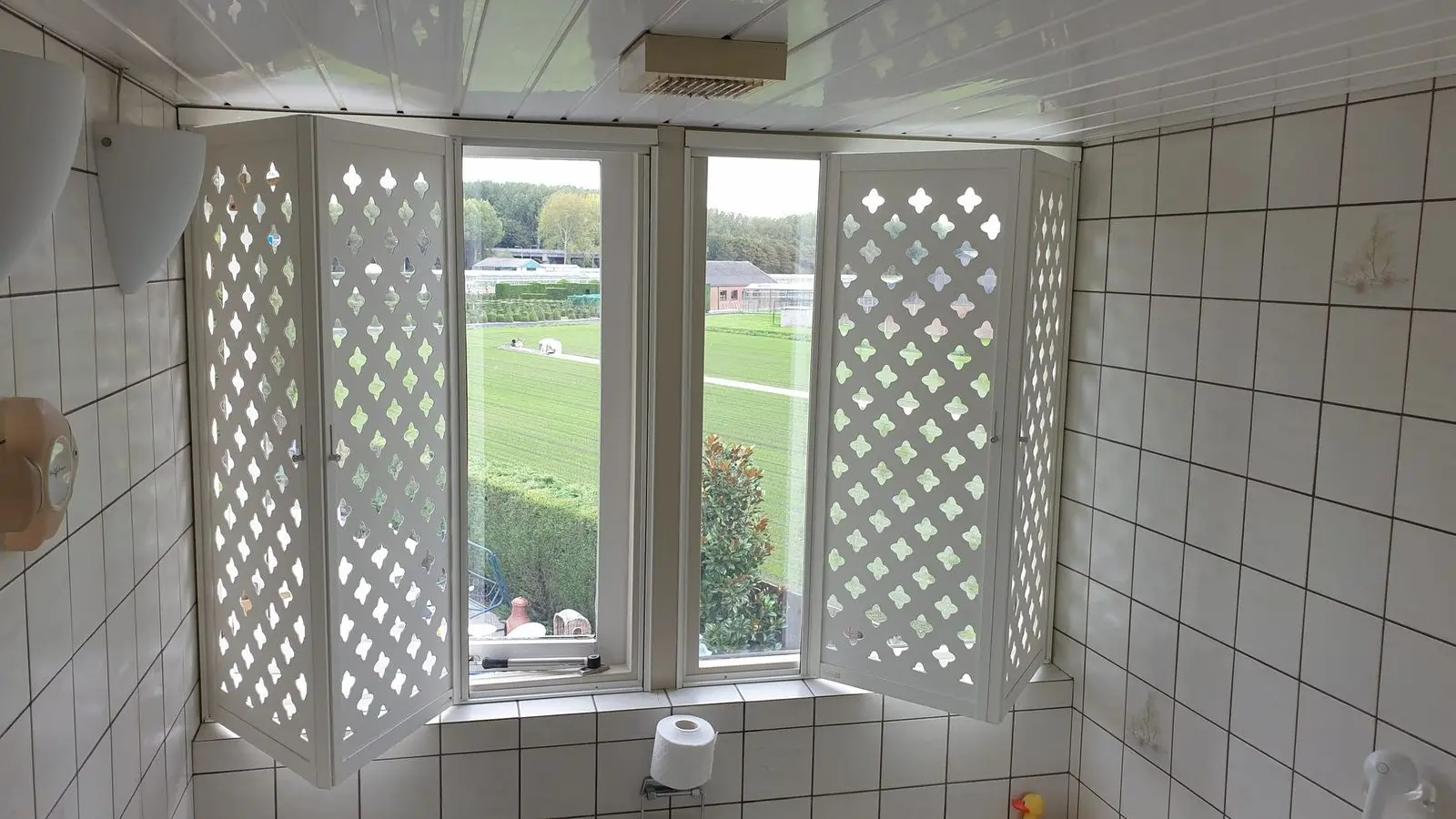 Witte panelen met ruitpatroon opengevouwen in een betegelde ruimte