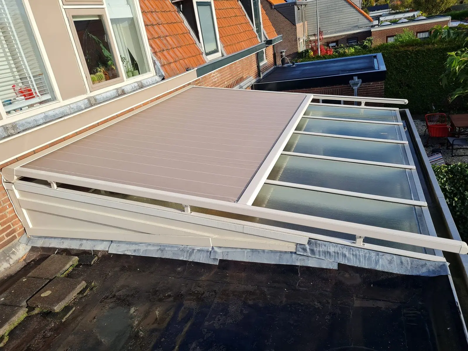 Taupe doek half uitgerold over het glazen dak van een serre