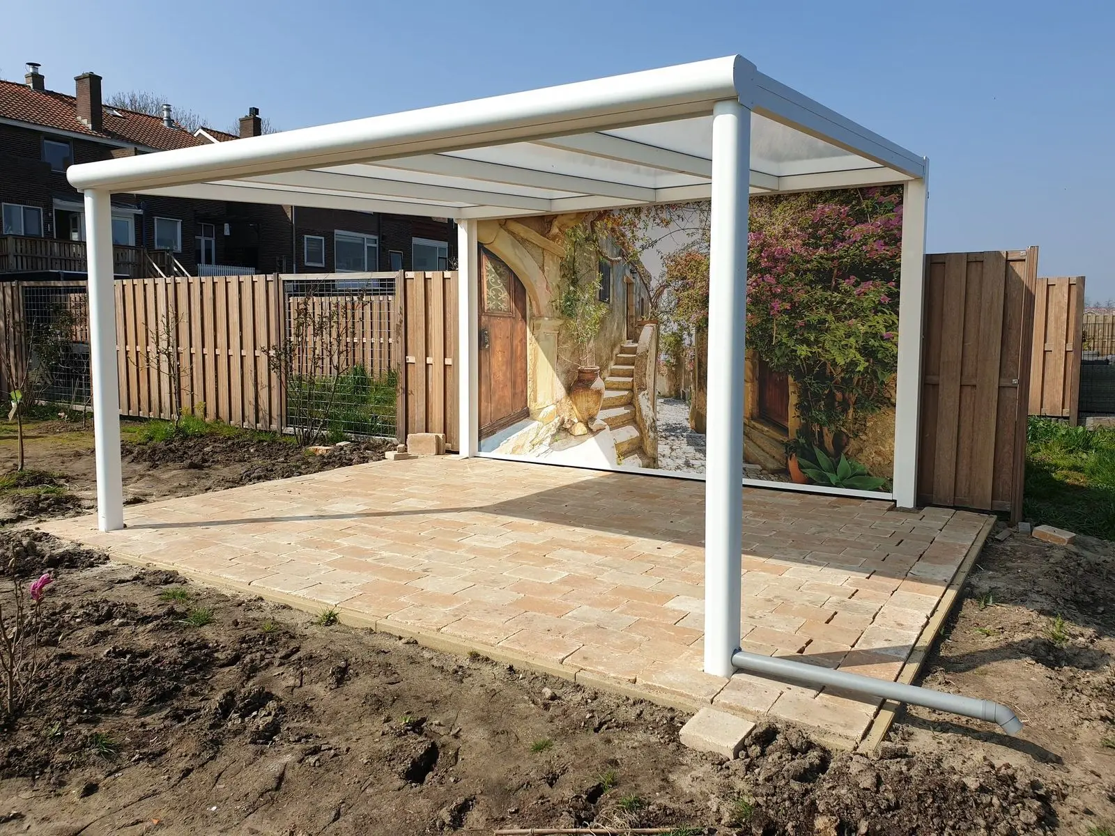 Witte overkapping met een doek aan de zijkant, in een nieuw aangelegde tuin