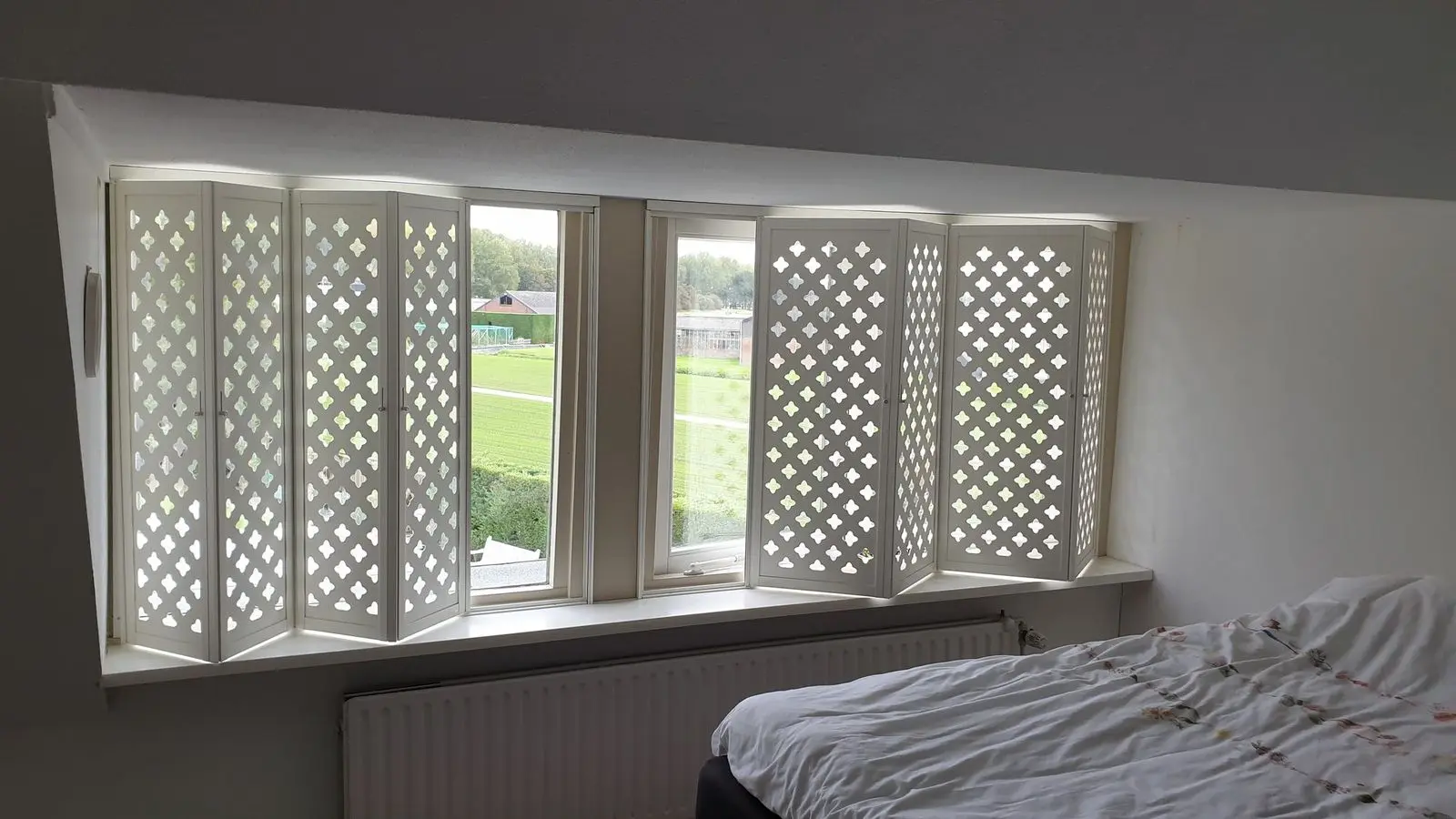 Witte panelen met ruitpatroon deels opengevouwen in een slaapkamer