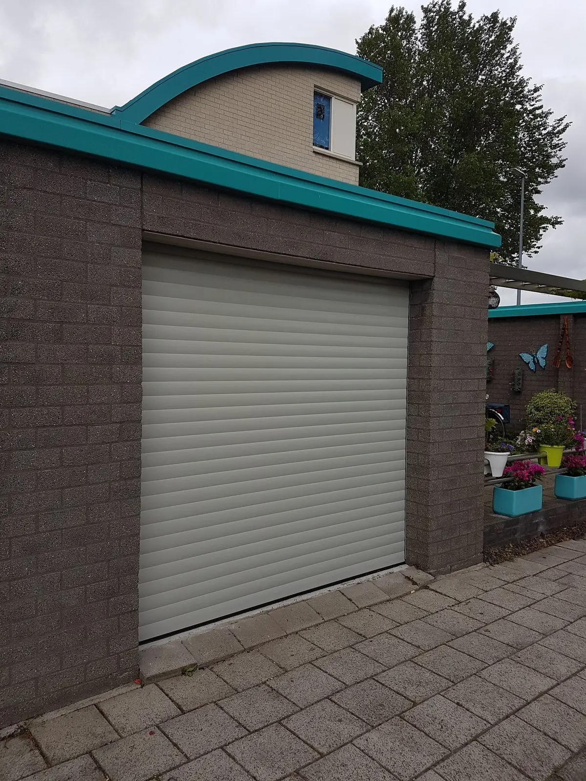 Lichtgrijze rolpoort in een garage van donkere baksteen