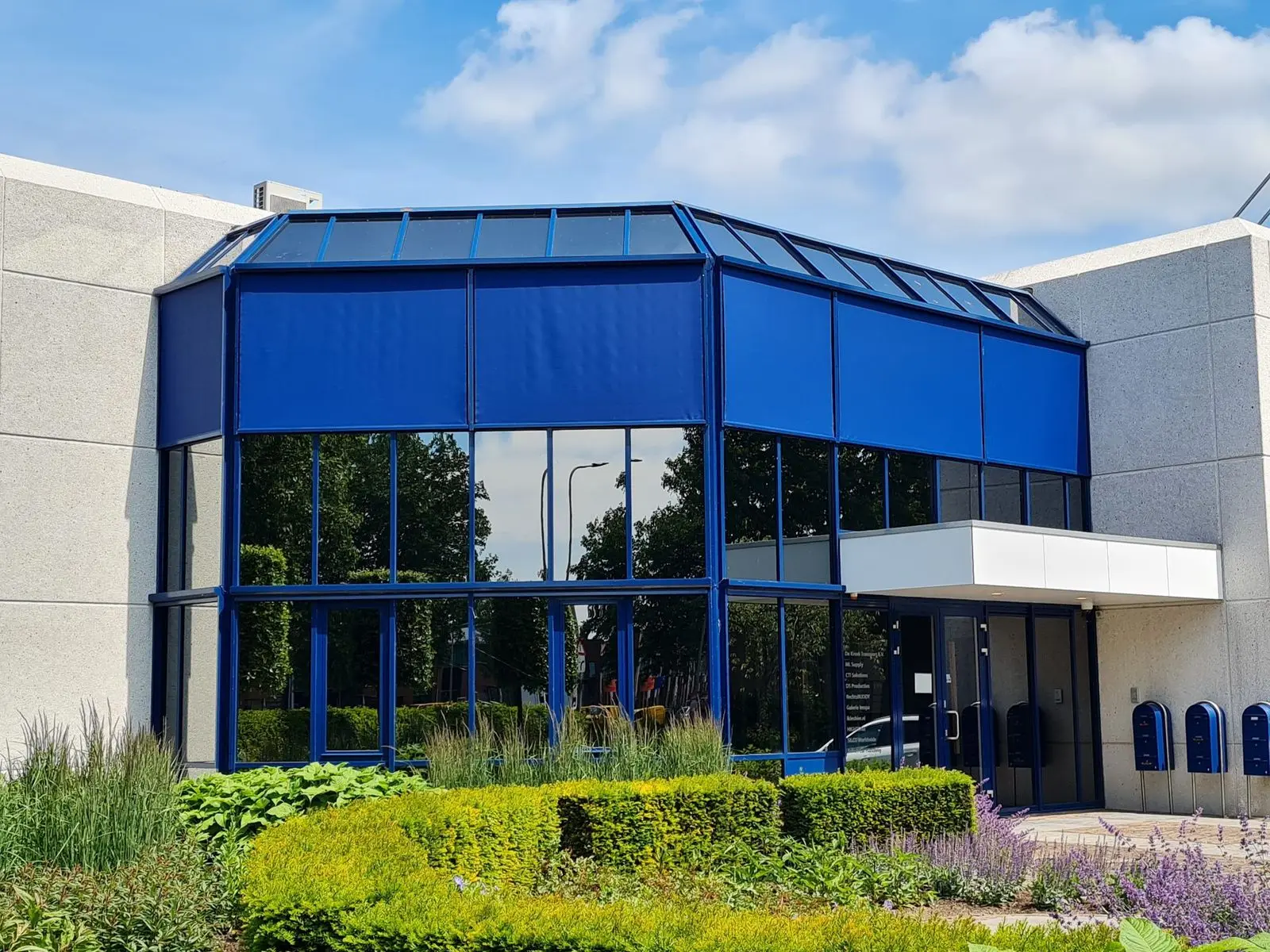 Blauwe zipscreens rondom de glazen gevel van een kantoorgebouw