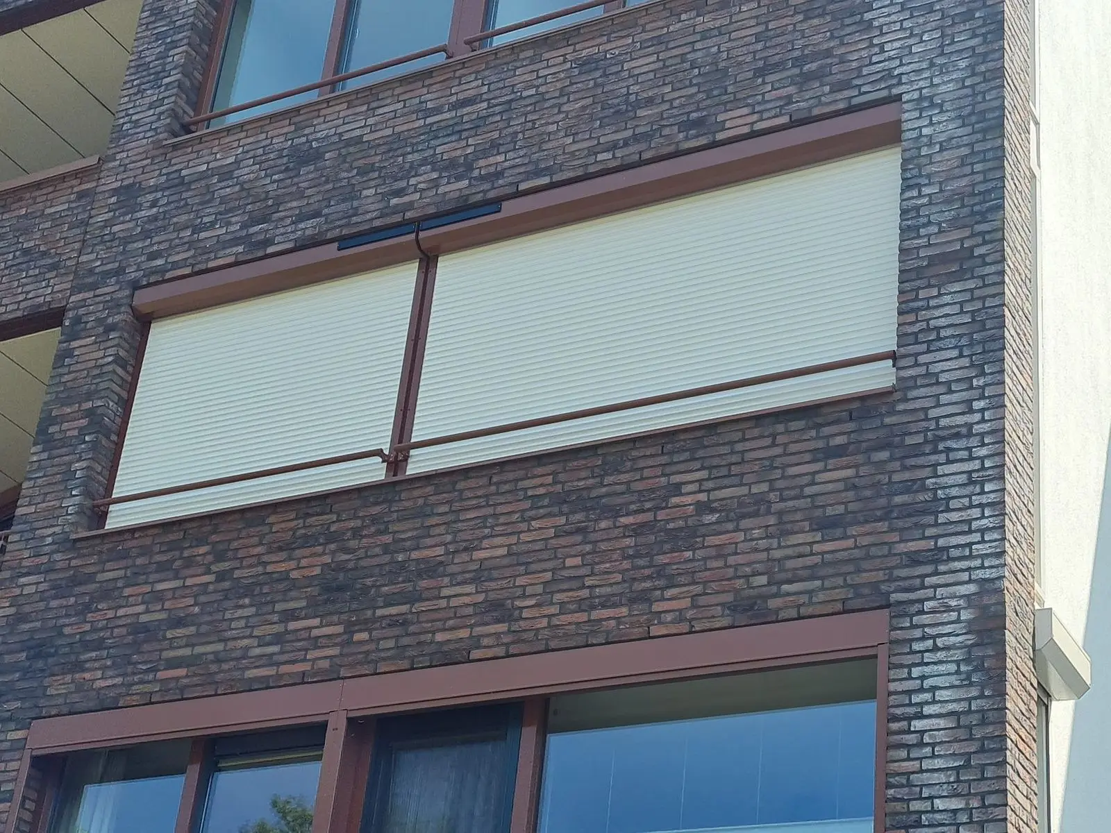 Witte rolluiken half neergelaten voor de ramen van een appartement