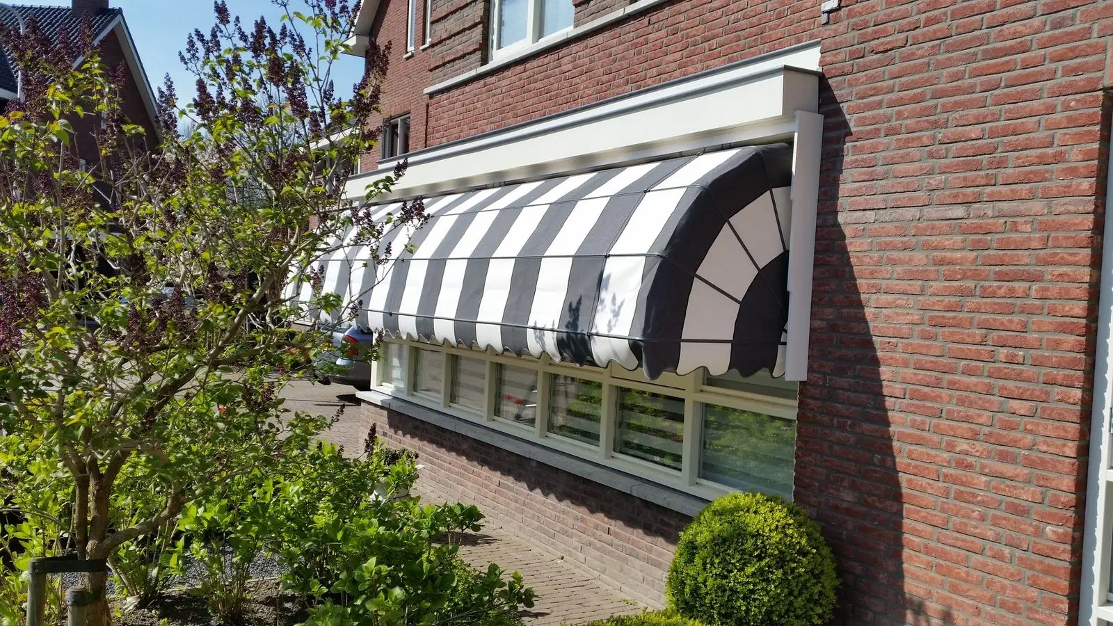 Markies met zwart-wit gestreept doek boven de ramen van een hoekwoning