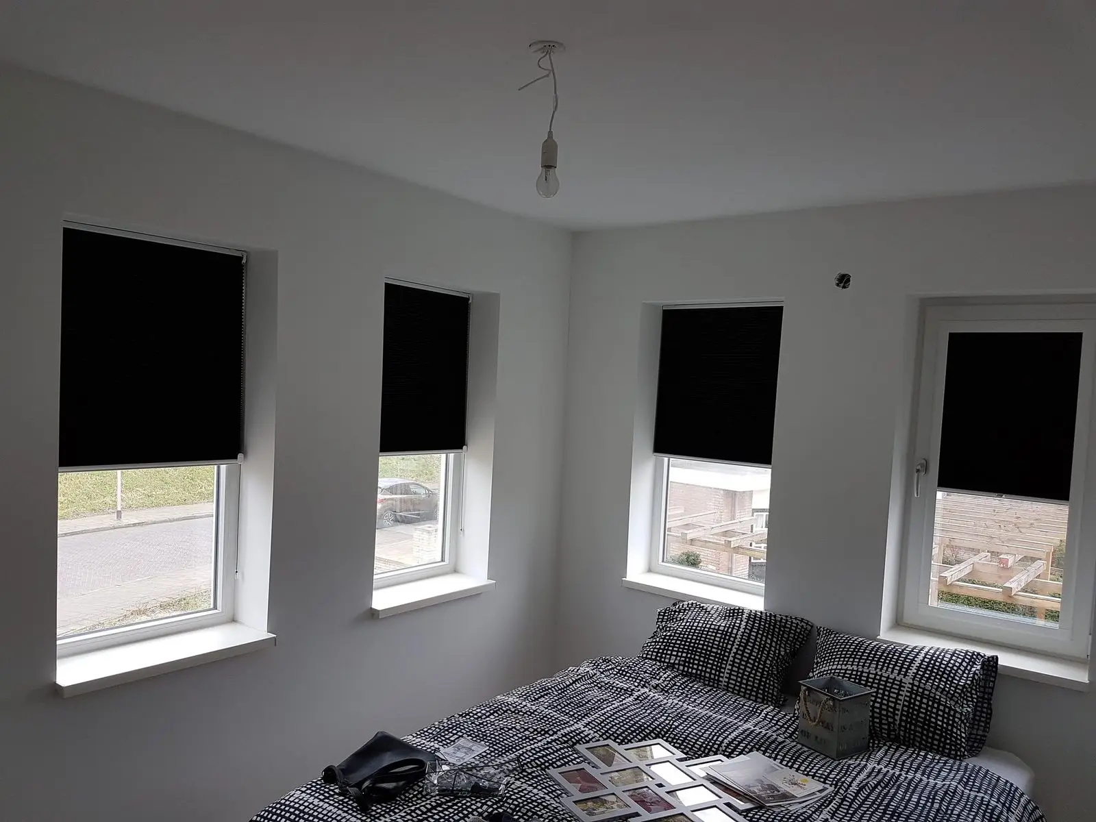 Zwarte plissés voor vier ramen in een slaapkamer